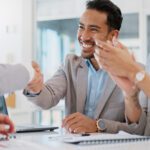 Enthusiastic businessman shaking hands with a coworker in a conference room. 