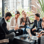 group of women and men conversing, smiling in an outdoor space with drinks in hand